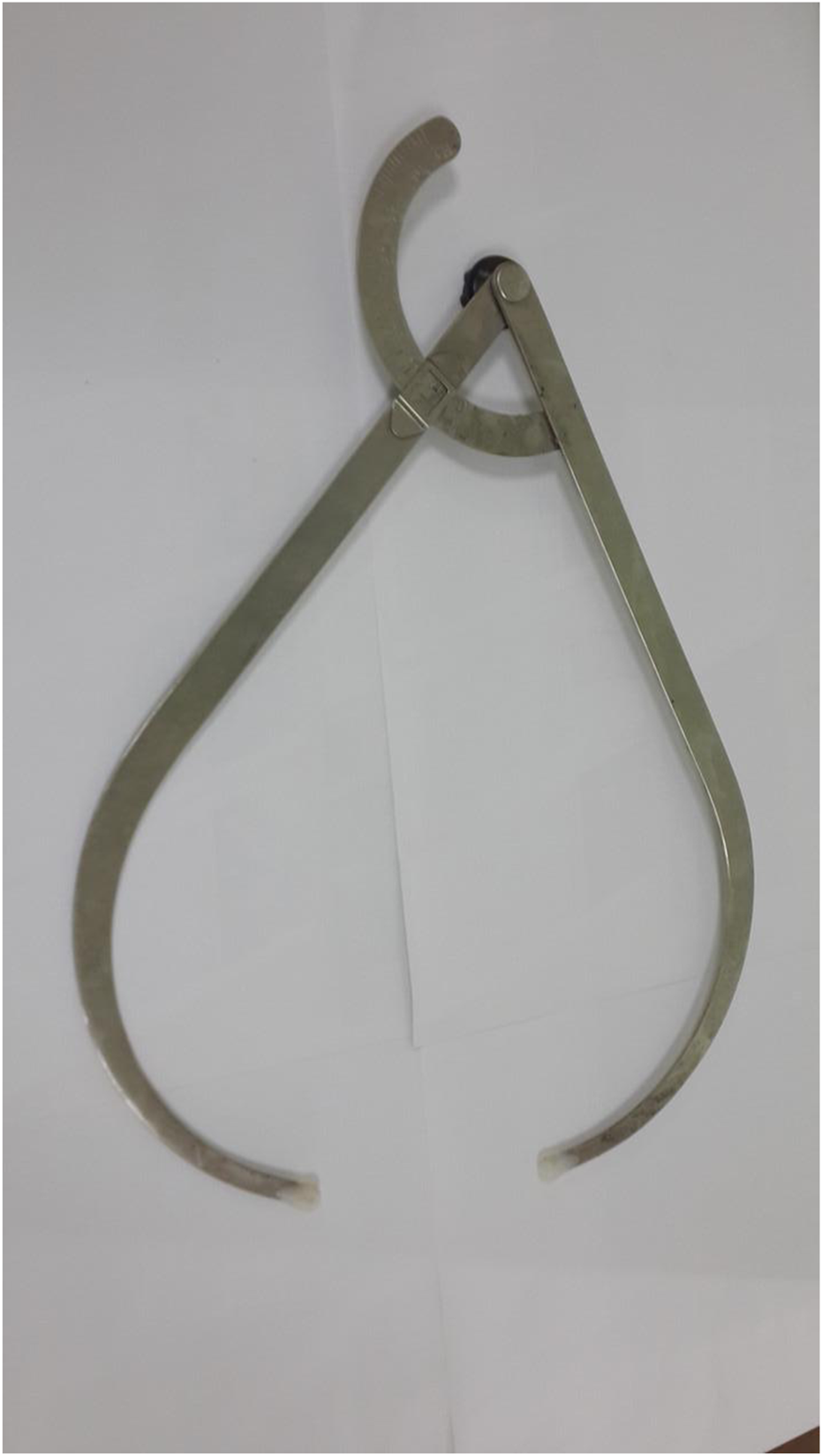 A pair of metal calipers with a curved arm and a straight arm set at a right angle. The device is open, designed for measuring external dimensions accurately.